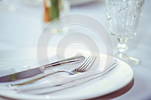 Restaurant table setout with white plates and silverware