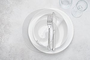 Restaurant table setting with white plates, glasses and cutlery