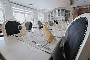 Restaurant tables and chairs with glassware and napkins