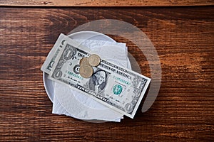 Restaurant tips or gratuity. Banknotes and coins on a plate photo