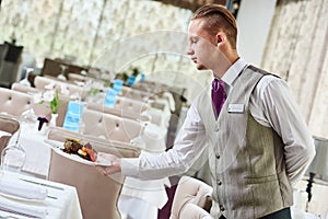 Restaurant waiter serving table with food photo
