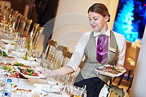 Restaurant waitress serving table with food