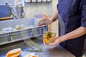 Restaurant worker holding souse in a bowl in kitchen photo