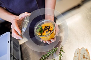 Restaurant worker holding souse in a bowl in kitchen photo