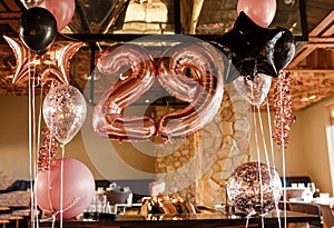 Restaurante room decorated for a birthday party with pink, black and transparent baloons of different sizes, large