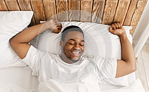 Rested African Man Waking Up Lying In Bed At Home photo