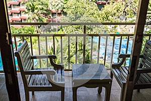 resting area of balcony with two couch armchair sofa outdoor. high view. sun deck of resort. Swimming pool view and palm trees.