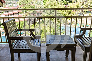 resting area of balcony with two couch armchair sofa outdoor. high view. sun deck of resort. Swimming pool view and palm trees.