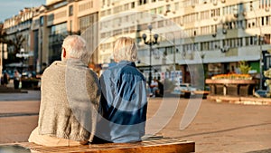 Resting. Back view of senior couple in casual clothes sitting on the bench together
