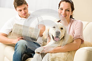 Resting joyful couple sitting and petting dog