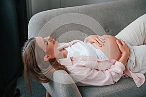 Resting on the sofa. Beautiful pregnant woman is indoors at home