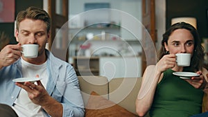 Resting spouses drinking tea sofa together zoom on. Love couple enjoying coffee