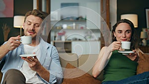 Resting spouses drinking tea sofa together zoom on. Love couple enjoying coffee