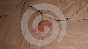 Restless feet of a kid boy on a sheet under a blanket at night. Baby child girl with bare legs tosses and does not fall