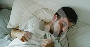 Restless insomniac feeling anxious while having a nightmare in bed. Scared man gets frighted and looks terrified after