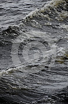 Restless water, dark waves with foam close-up