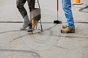 Restoration work applying liquid sealer to asphalt a road protective coat