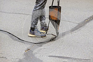 Restoration work sealing cracks applying liquid sealer to asphalt a road protective coat on roadway