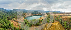 Restoration works in copper mining area with lake in open mine pit and spoil heaps covered with pine trees