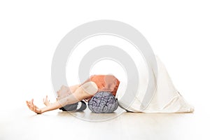 Restorative yoga with a bolster. Young sporty attractive woman in bright white yoga studio, stretching and relaxing