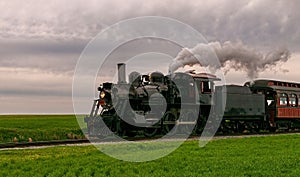 Restored steam passenger train traveling by on a cloudy day.