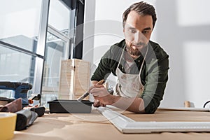 Restorer in apron holding paintbrush near