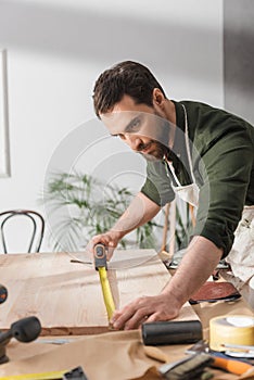 Restorer in apron measuring wooden board