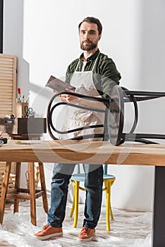 Restorer holding sandpaper and looking at