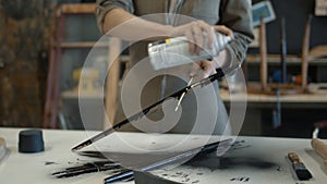 Restorer spraying a black wooden detail, a female worker