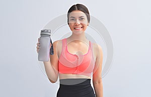 Restoring water balance. Attractive and young woman in sports wear keeping bottle in hand and smilingd