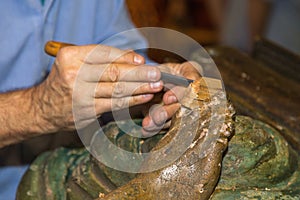 Restoring Wooden Sculpture: Close-up of Restorer working on Religious Works