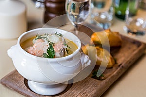 Restourant serving dish - salmon soup on wooden board with pie,