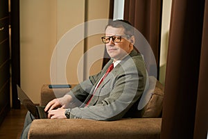 Restrained middle-aged man sits in a chair with a laptop