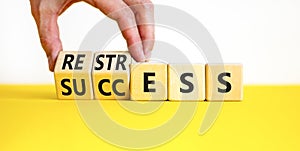 Restress for success symbol. Concept words Restress and Success on wooden cubes. Businessman hand. Beautiful yellow table white