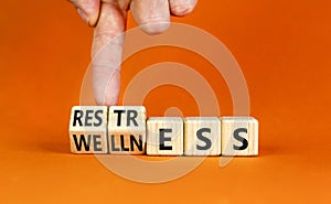 Restress for wellness symbol. Concept words Restress and Wellness on wooden cubes. Businessman hand. Beautiful orange table orange