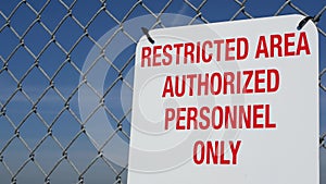 Restricted area, authorized personnel only sign in USA. Red letters, keep off warning on metal fence, United States border symbol