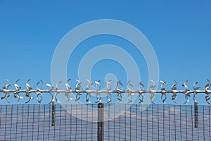 Metal security fence against a clear blue sky background