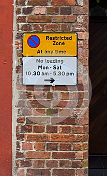 Restricted Zone Sign on The Red Brick Wall and No Loading Times