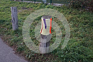 A restrictive roadside pole decorated with knitwear against a background of grass with hoarfrost in December. Berlin, Germany