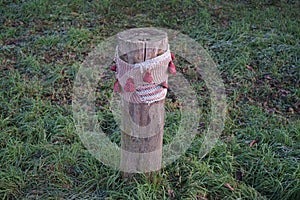 A restrictive roadside pole decorated with knitwear against a background of grass with hoarfrost in December. Berlin, Germany