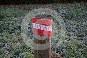 A restrictive roadside pole decorated with knitwear against a background of grass with hoarfrost in November. Berlin, Germany