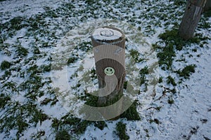 A restrictive roadside post decorated with knitwear against the background of grass under the snow in January. Berlin, Germany