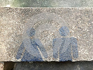 Restroom sign with man and woman blue color painting on cement floor.