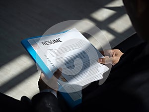 Resume documents or curriculum vitae paper in hands of a unemployed man applicant in a suit sitting waiting for a job interview