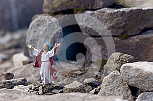 Resurrected Jesus Christ standing in front of the entrance to the grave - tomb. He stands among the rocks. photo