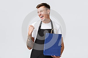 Retail store, shopping and employees concept. Cheerful happy salesman enjoying finally working after covid-19, fist pump