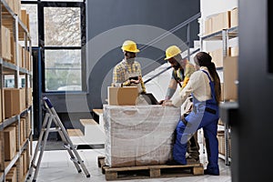 Retail storehouse workers discussing customer online order on laptop