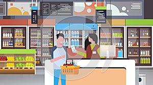 Retail woman cashier at checkout supermarket giving receipt bill man customer holding basket with food shopping concept