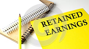 RETAINED EARNINGS text written on a yellow paper with notebook