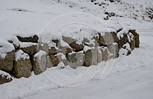 Retaining wall made of granite boulders by the road. the snow fit all around, only the wall remained visible in its beautiful text